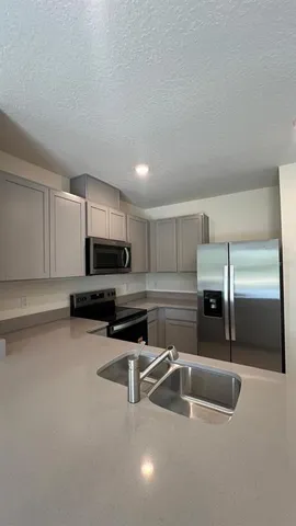 a kitchen with stainless steel appliances a sink a stove a microwave a counter top space and cabinets