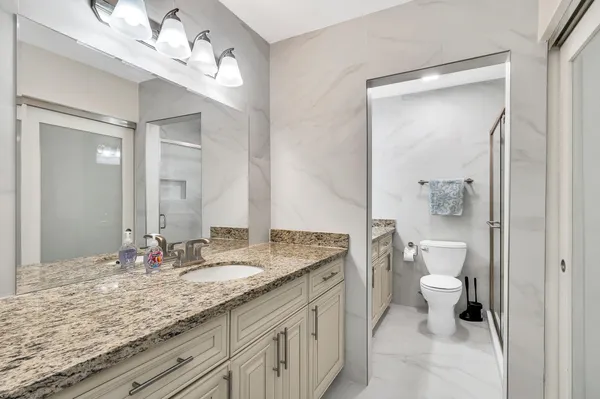 a bathroom with a granite countertop sink a toilet and a mirror