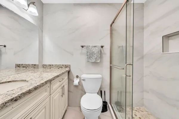 a bathroom with a granite countertop sink toilet and shower