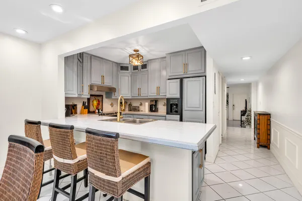 a kitchen with stainless steel appliances kitchen island granite countertop a table chairs microwave and refrigerator