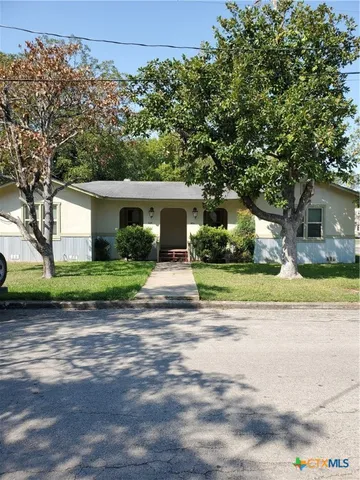 a view of white house with a big yard and large trees