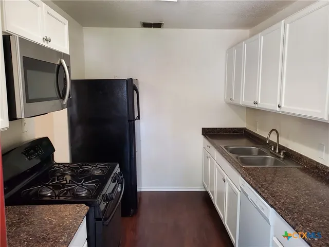 a kitchen with granite countertop stainless steel appliances a sink stove and refrigerator