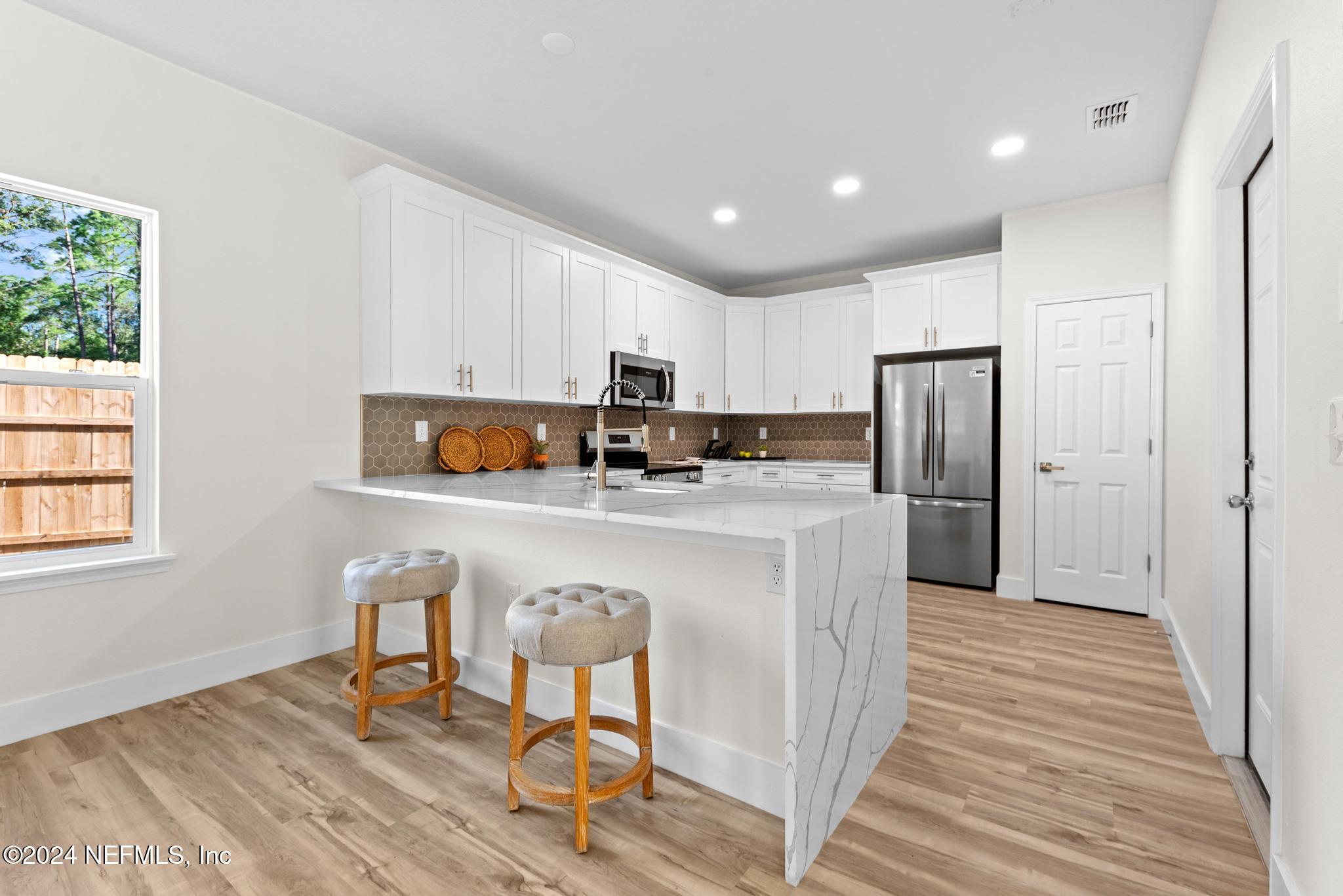 12731 Old St Augustine Road Jacksonville, FL 32258 - Photo 9 of 24 a kitchen with stainless steel appliances granite countertop a refrigerator a stove a sink cabinets and a dining table with wooden floor