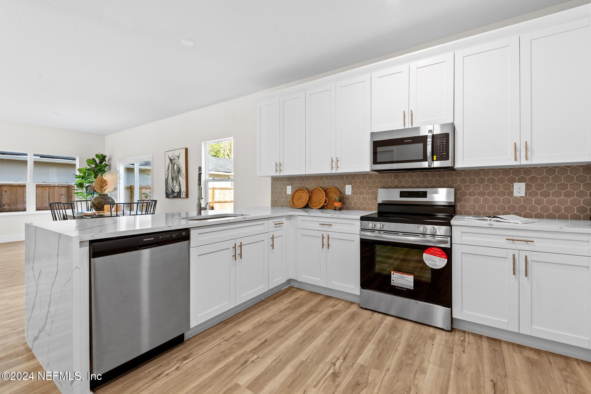 12731 Old St Augustine Road Jacksonville, FL 32258 - Photo 10 of 24 a kitchen with stainless steel appliances granite countertop a stove top oven a sink dishwasher and a microwave oven with cabinets