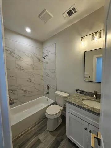 a bathroom with a granite countertop toilet a sink and bathtub