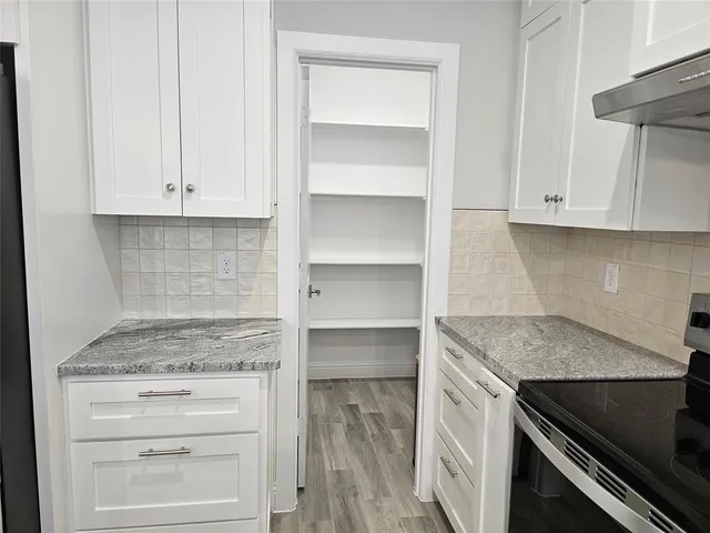 a kitchen with granite countertop white cabinets and a stove