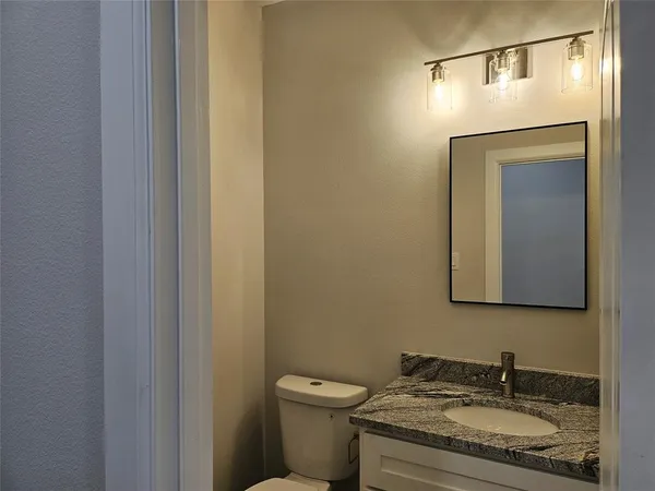 a bathroom with a granite countertop sink toilet and mirror