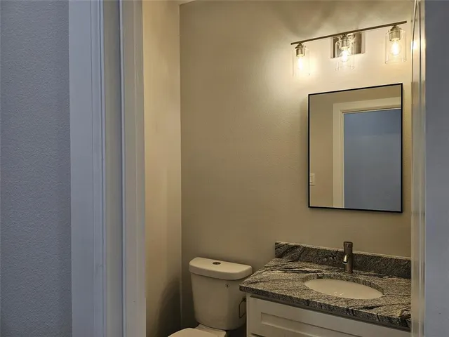 a bathroom with a granite countertop sink toilet and mirror