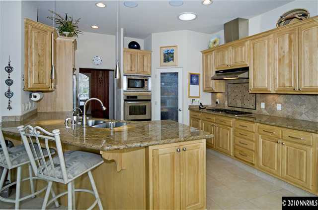 3265 Lapwing Lane Reno, NV 89509 - Photo 3 of 9 a kitchen with stainless steel appliances kitchen island granite countertop a table chairs and a refrigerator