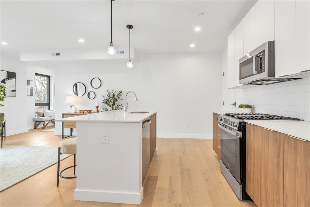 3992 Washington Street, Unit 302 Boston, MA 02131 - Photo 3 of 29 a kitchen with stainless steel appliances granite countertop a sink a stove and a wooden floors