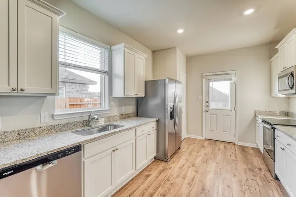 a kitchen with white cabinets and wooden floors