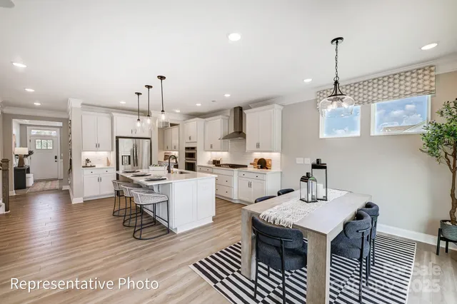a kitchen with stainless steel appliances a dining table chairs stove and white cabinets
