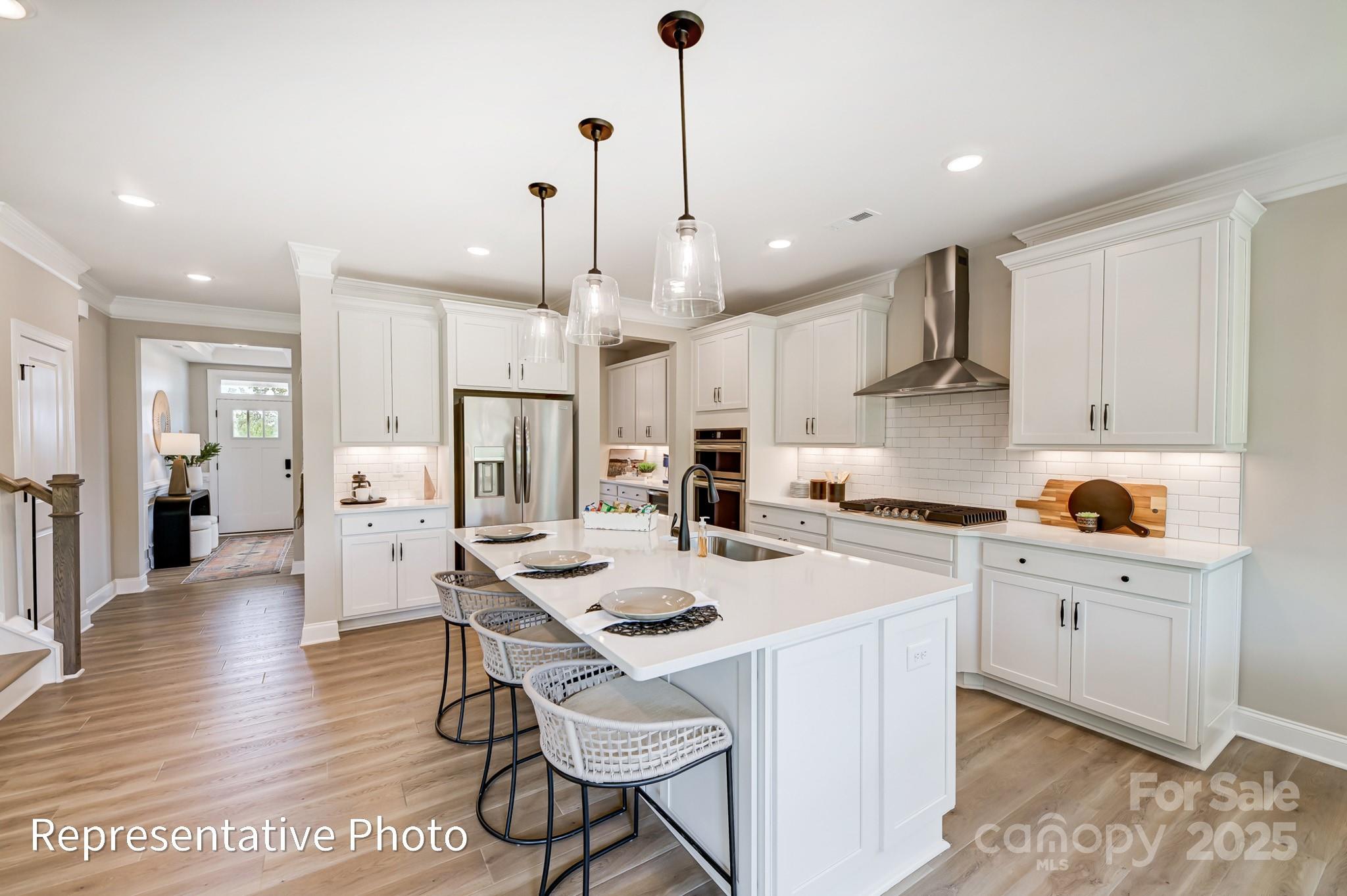 5038 Mclaughlin Loop Waxhaw, NC 28173 - Photo 5 of 25 a kitchen with stainless steel appliances kitchen island granite countertop a sink a stove a refrigerator and white cabinets with wooden floor