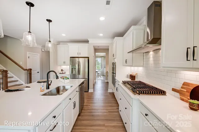a kitchen with counter top space a sink a refrigerator and chairs