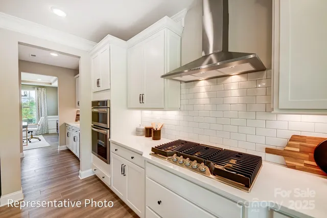 a kitchen with stainless steel appliances a stove a sink and white cabinets