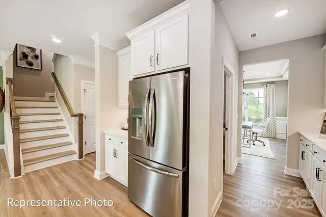 a view of a kitchen with refrigerator and wooden floor
