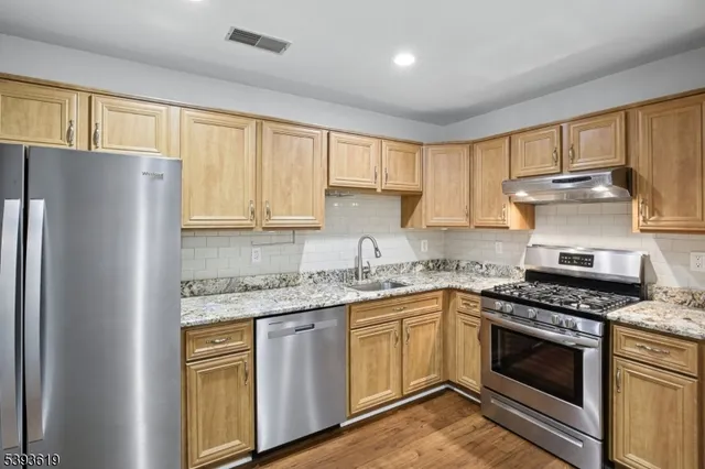 a kitchen with granite countertop a sink stainless steel appliances and cabinets