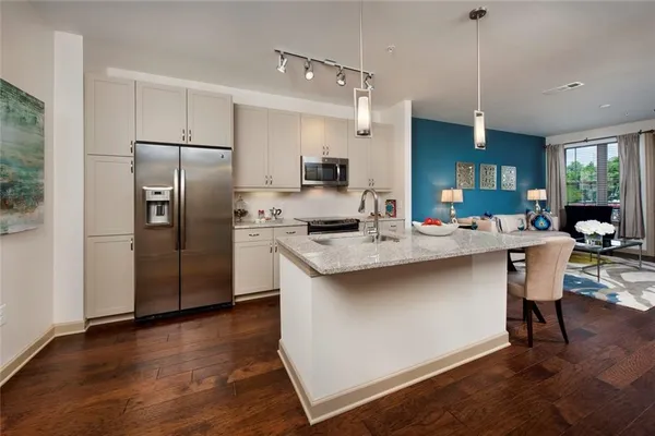 a kitchen with stainless steel appliances a sink stove refrigerator and a wooden floor