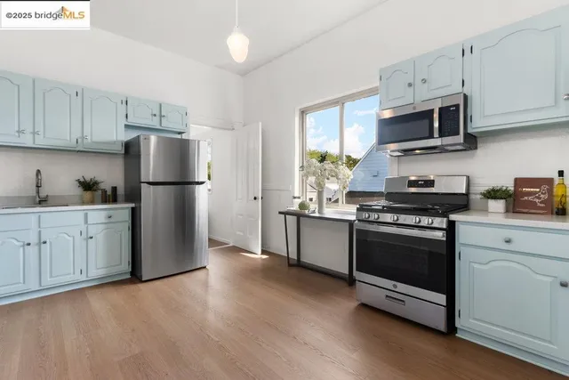 a kitchen with stainless steel appliances white cabinets white stove a sink and a refrigerator