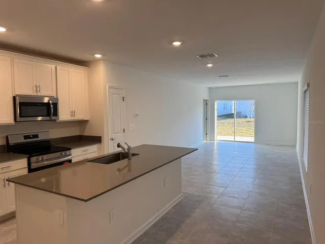 a kitchen with kitchen island a sink a stove a microwave a counter top and cabinets