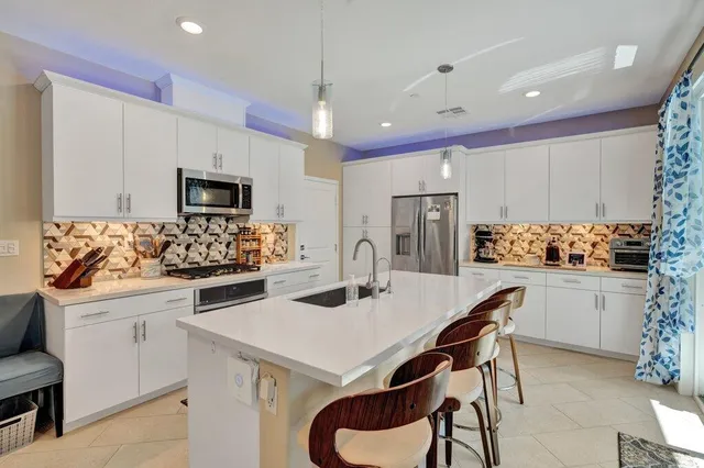 a kitchen with a sink a stove a refrigerator and white cabinets with wooden floor