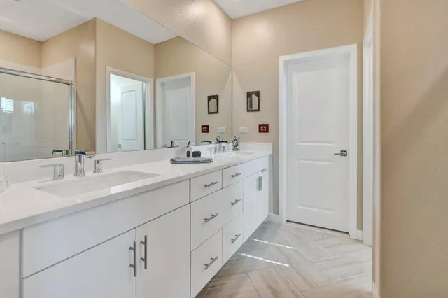 a bathroom with a glass door shower a sink and a mirror