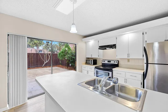 a kitchen with kitchen island a large counter top space appliances and living room view