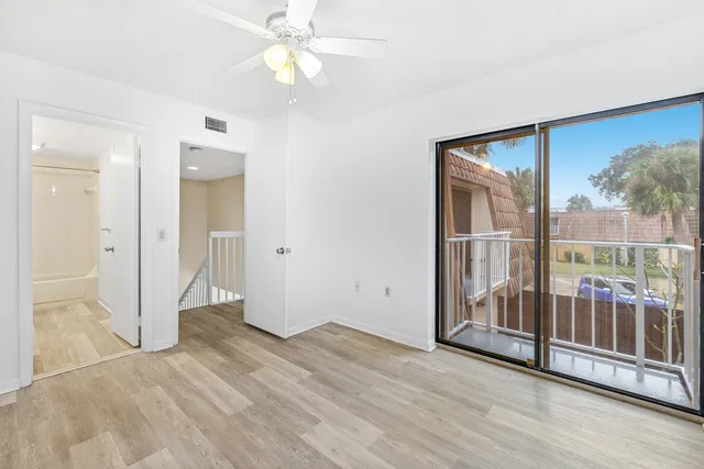 an empty room with wooden floor and a ceiling fan