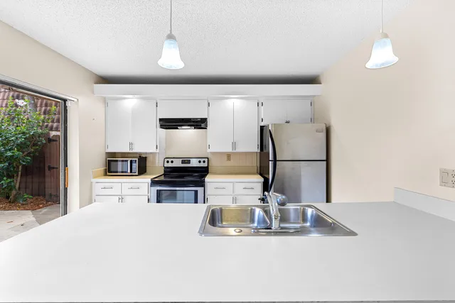 a kitchen with a sink a counter top space cabinets and stainless steel appliances