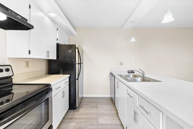 a kitchen with granite countertop a sink stove and refrigerator