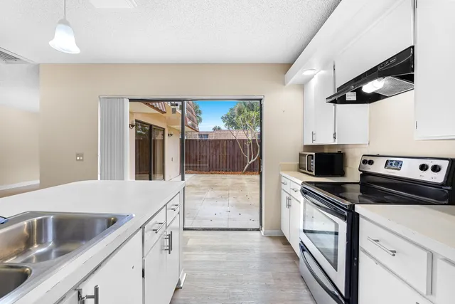 a kitchen with granite countertop a sink a stove and cabinets
