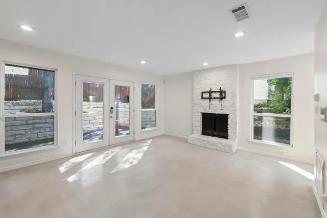 a view of an empty room with a fireplace and window