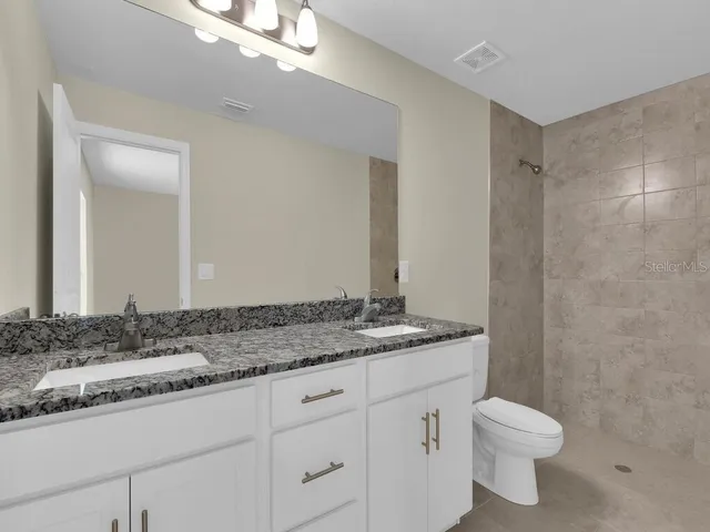 a bathroom with a granite countertop sink toilet and shower