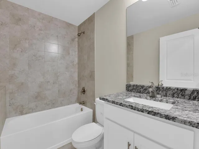 a bathroom with a granite countertop sink a toilet and bathtub