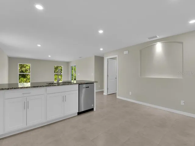 a kitchen with granite countertop white cabinets and sink