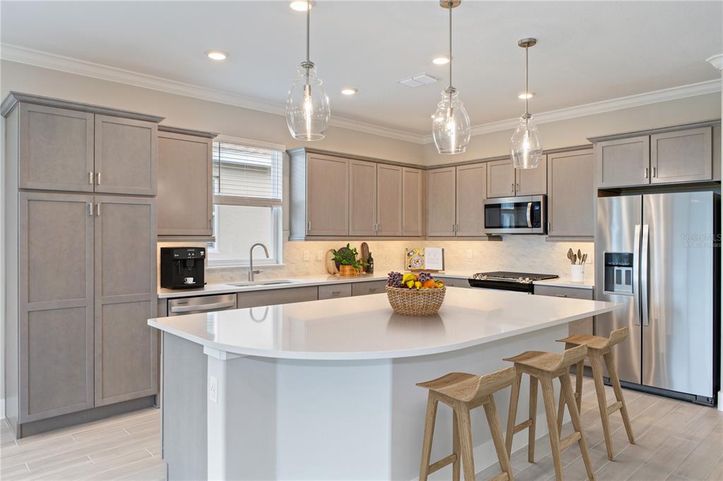 4516 Northwest 54th Terrace Ocala, FL 34482 - Photo 3 of 32 a kitchen with kitchen island a refrigerator a stove a sink and a center island
