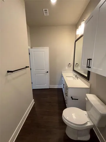 a bathroom with a toilet a sink and wooden floor