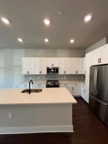 a kitchen with a sink a refrigerator and white cabinets