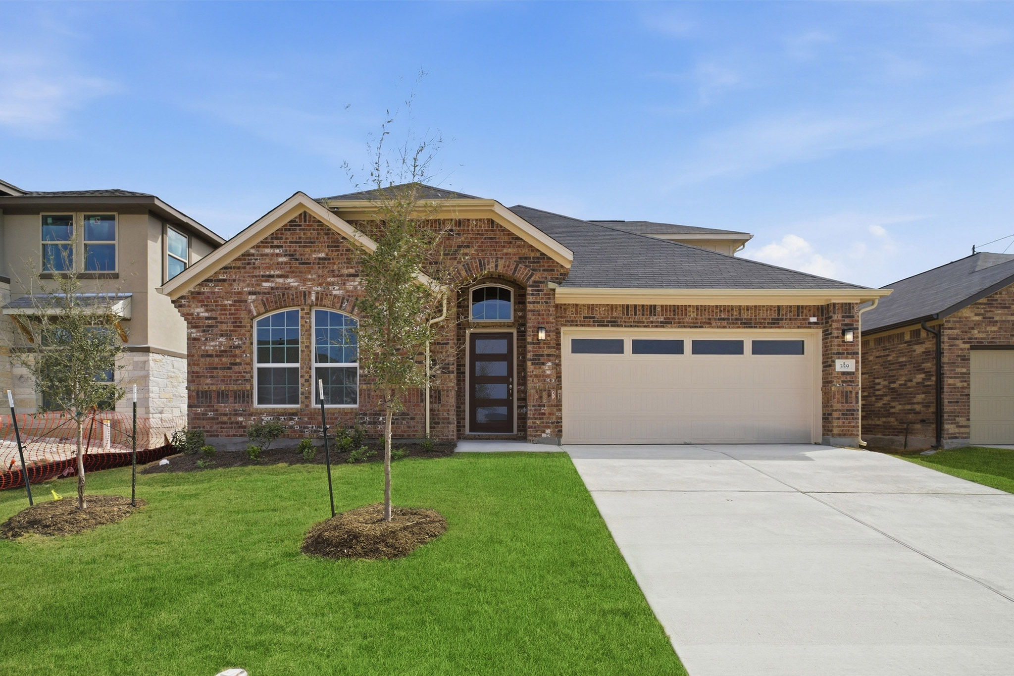 359 Grey Leaf Road Buda, TX 78610 - Photo 1 of 37 View of front of house with brick siding, an attached garage, concrete driveway, and a front yard