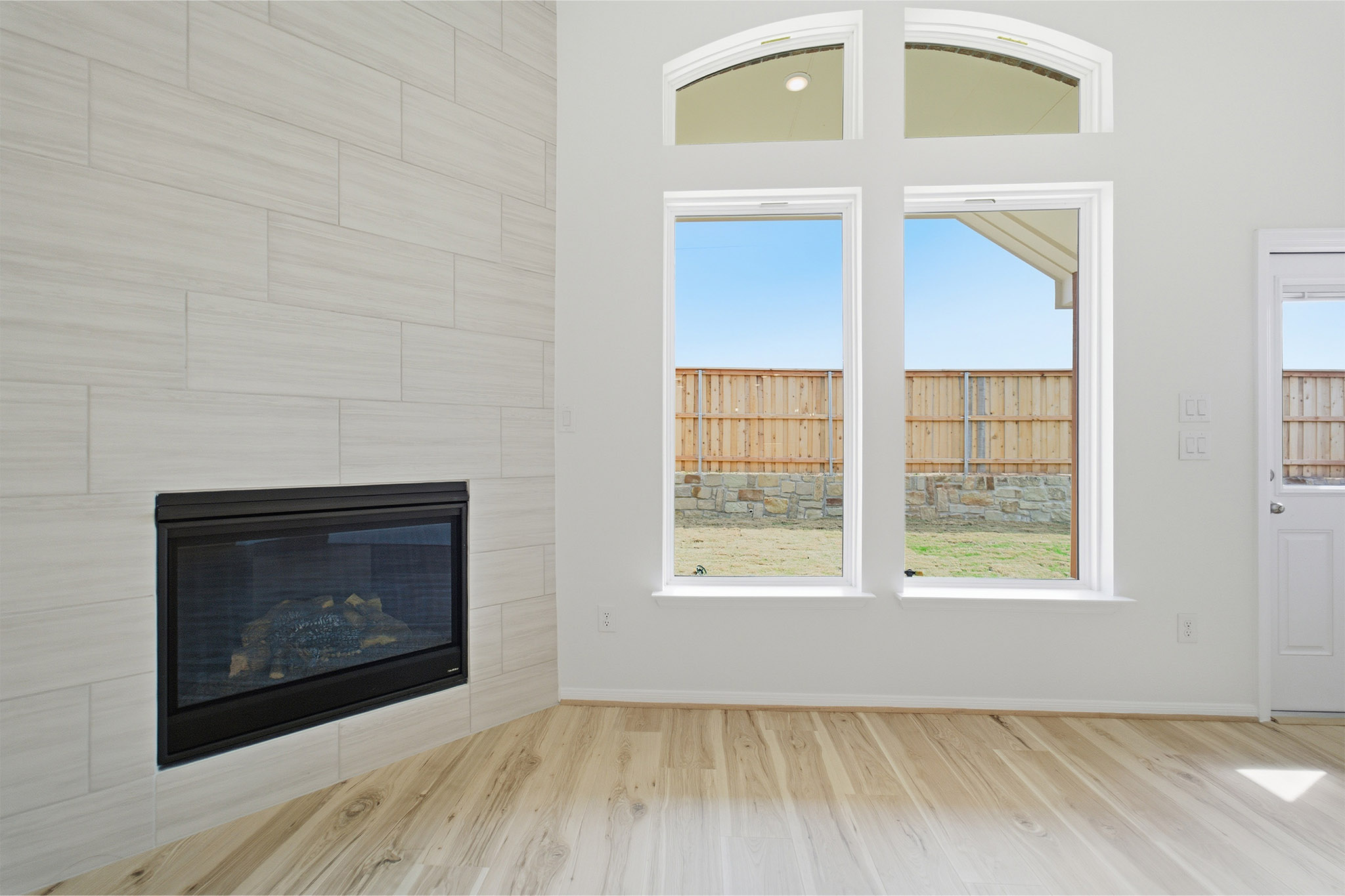 359 Grey Leaf Road Buda, TX 78610 - Photo 12 of 37 Unfurnished living room featuring light wood finished floors and a tile fireplace