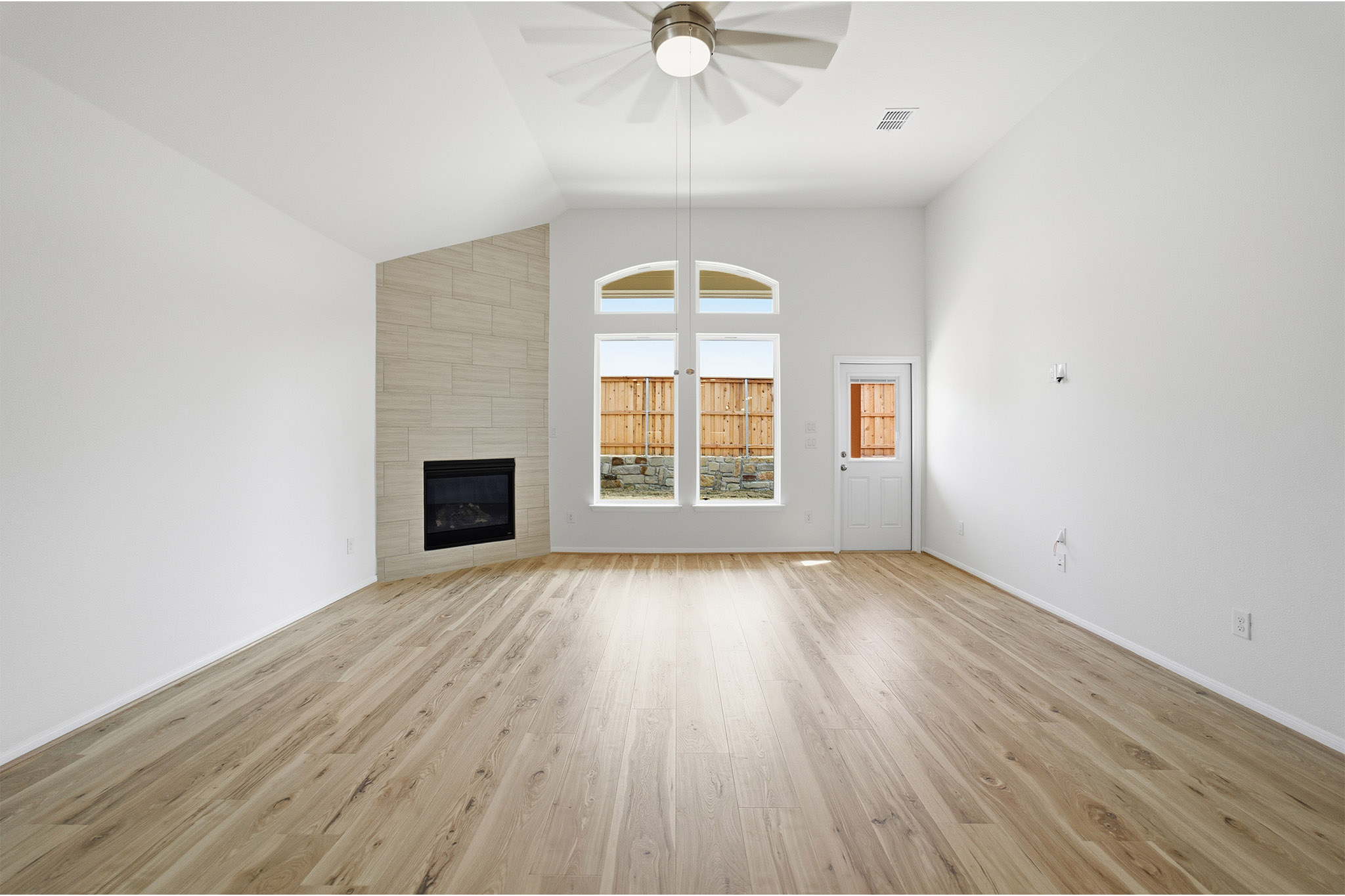 359 Grey Leaf Road Buda, TX 78610 - Photo 14 of 37 Unfurnished living room with light wood-style flooring, a tiled fireplace, ceiling fan, and lofted ceiling