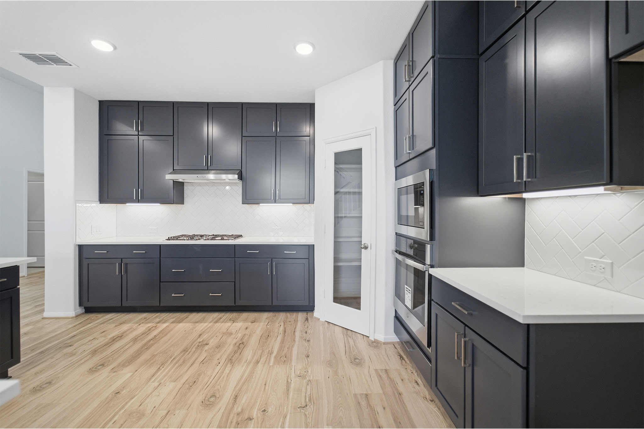 359 Grey Leaf Road Buda, TX 78610 - Photo 16 of 37 Kitchen with light stone counters, light wood finished floors, dark cabinetry, and recessed lighting