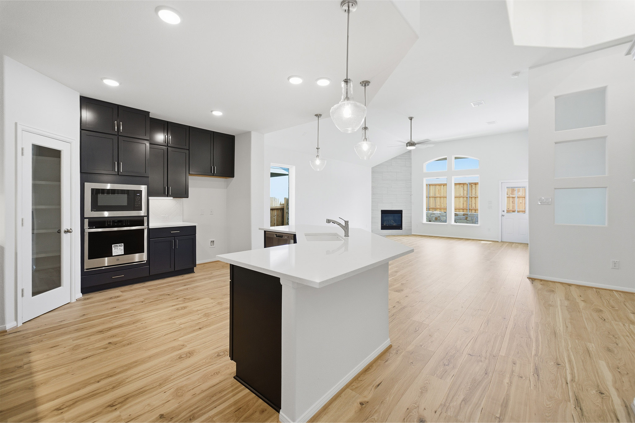 359 Grey Leaf Road Buda, TX 78610 - Photo 37 of 37 Kitchen with stainless steel appliances, light wood finished floors, a fireplace, open floor plan, and pendant lighting