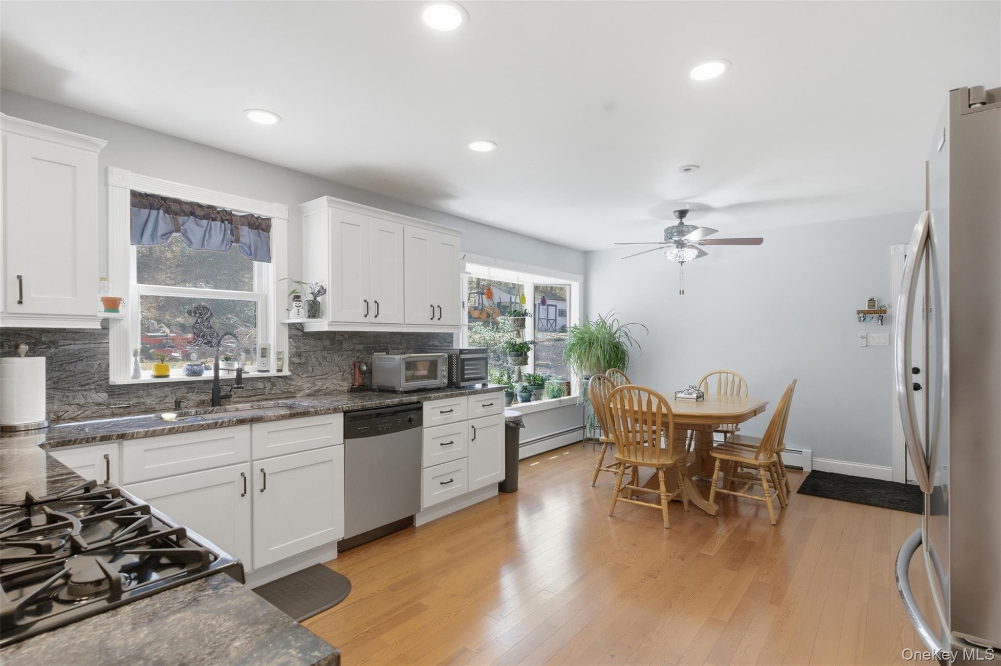 1285 Lakes Road Monroe, NY 10950 - Photo 5 of 45 a kitchen with stainless steel appliances a white table chairs and a wooden floor