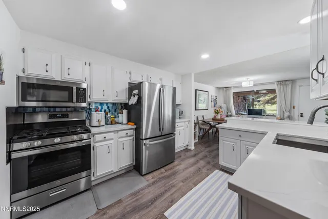 a kitchen with cabinets stainless steel appliances and wooden floor