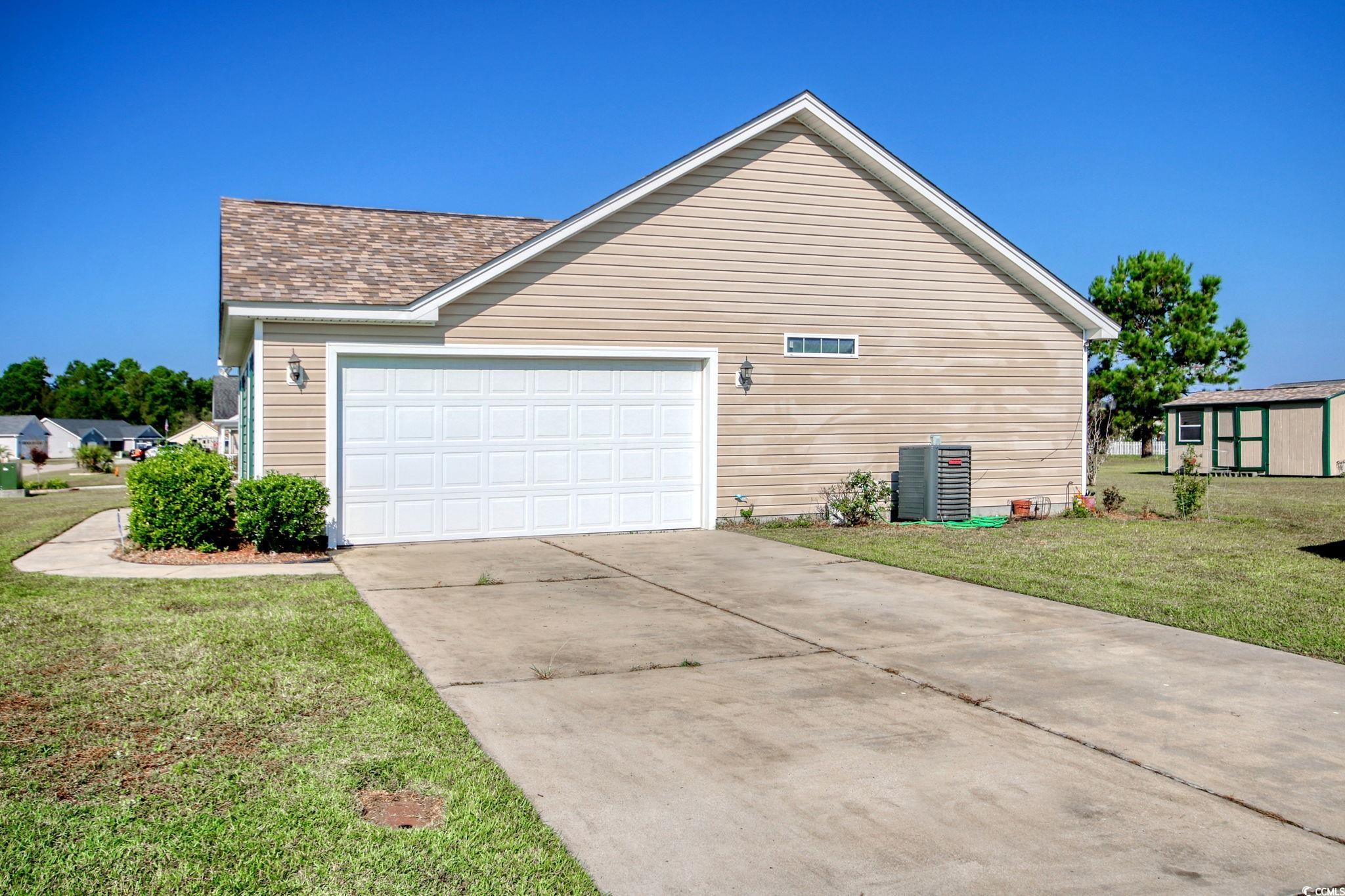 719 American Beech Street Loris, SC 29569 - Photo 20 of 20 View of property exterior featuring cooling unit, a yard, and a garage