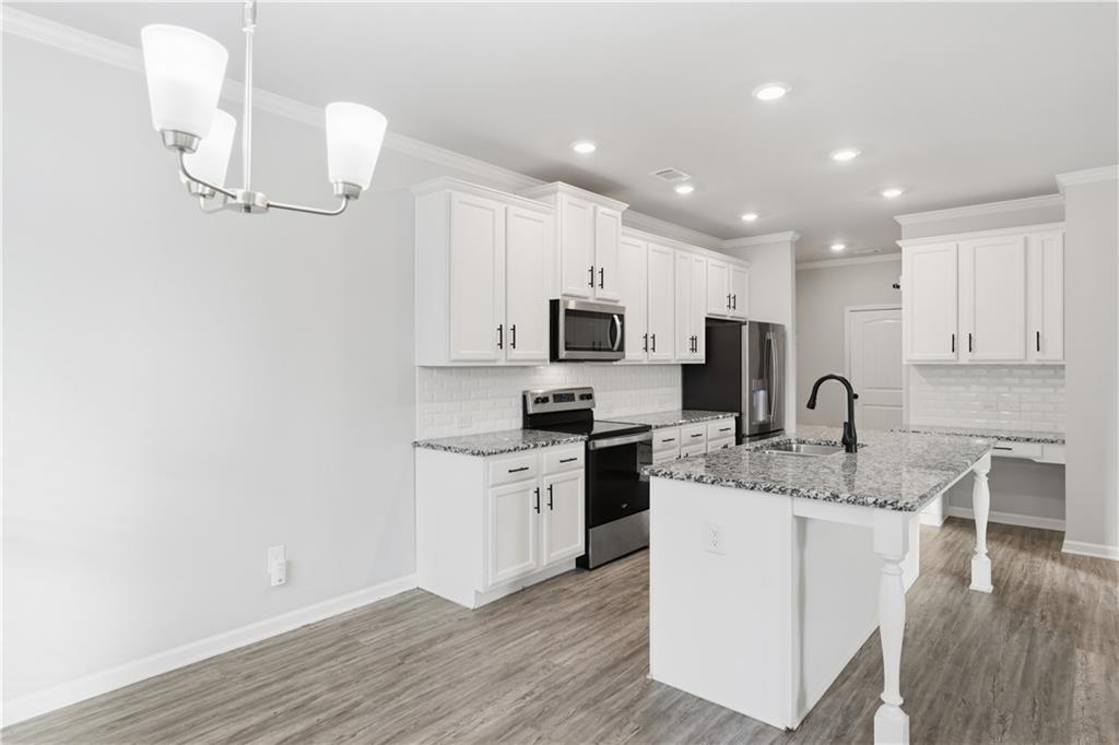 3244 Hawthorne Path Braselton, GA 30517 - Photo 11 of 48 a kitchen with stainless steel appliances granite countertop a sink a stove top oven a counter space and cabinets