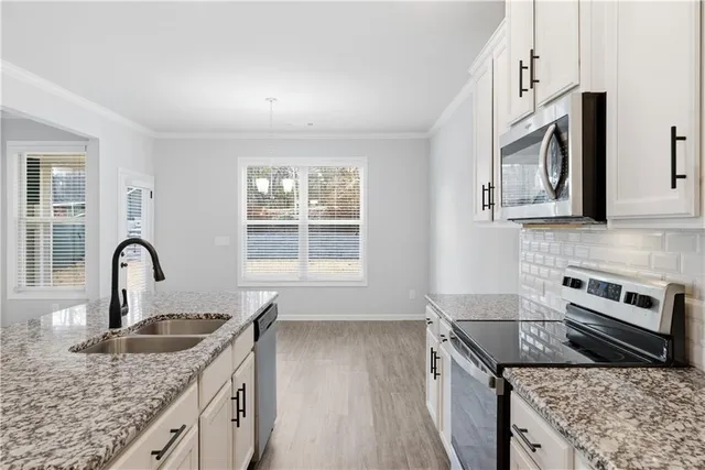 a kitchen with granite countertop a stove sink and microwave