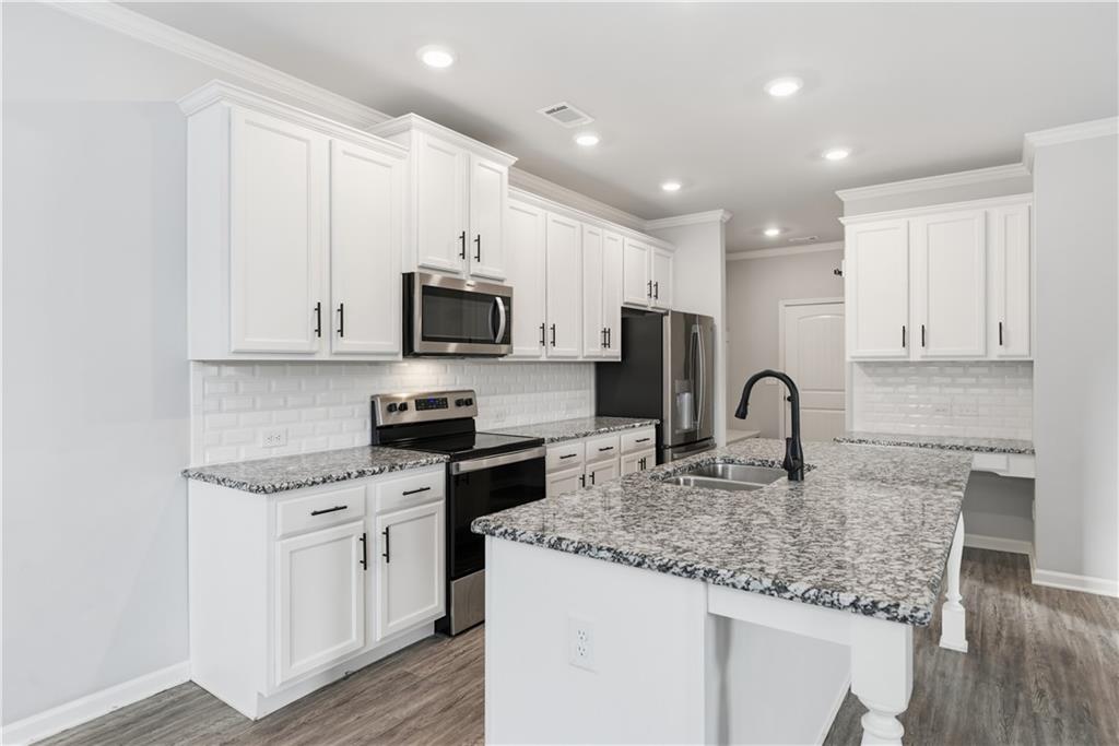3244 Hawthorne Path Braselton, GA 30517 - Photo 16 of 48 a kitchen with stainless steel appliances granite countertop a sink dishwasher a stove top oven a refrigerator with white cabinets and wooden floor