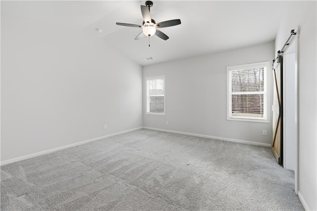 3244 Hawthorne Path Braselton, GA 30517 - Photo 27 of 48 an empty room with chandelier fan and windows